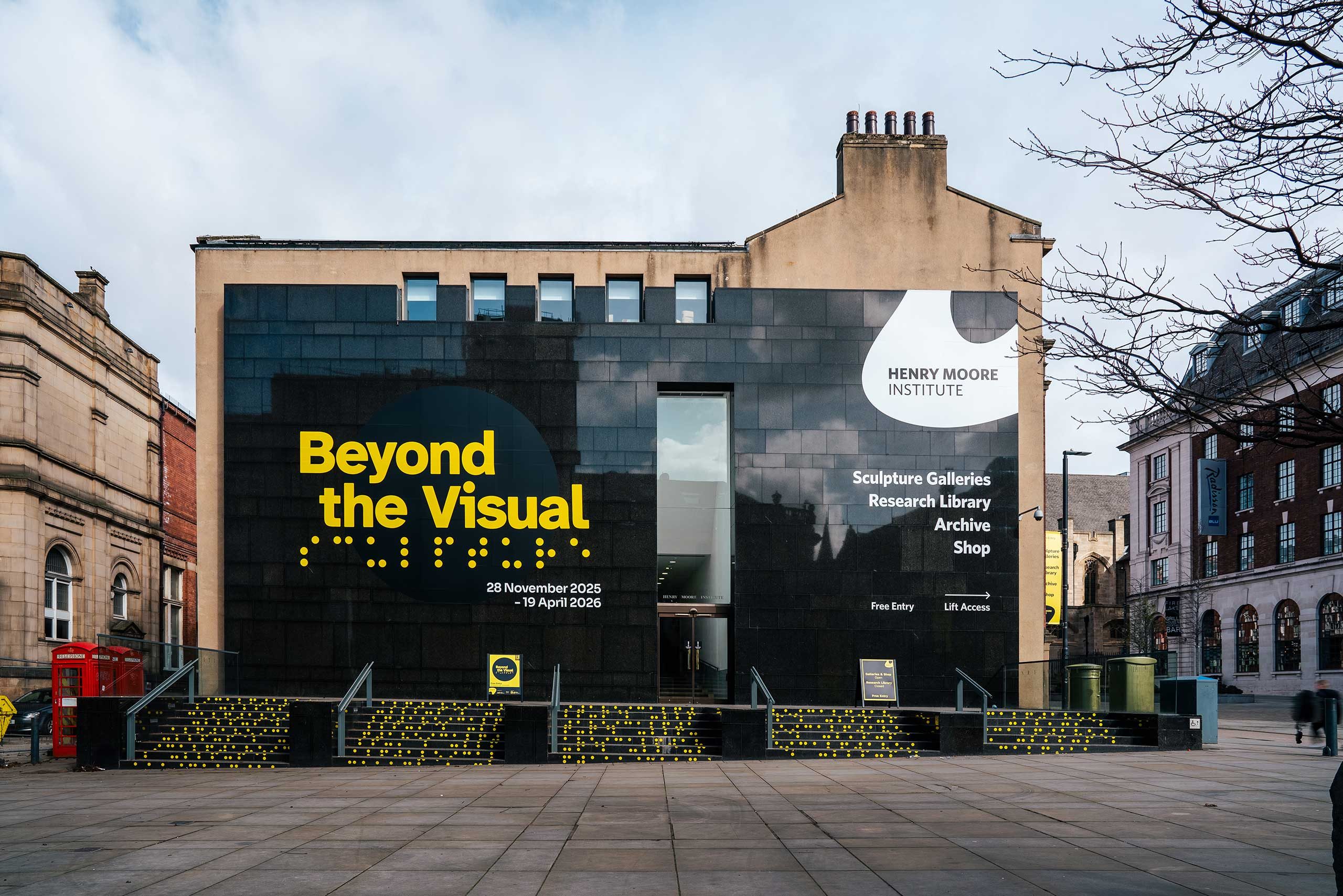 A three-story building with a black granite facade and steps leading up. Vinyl lettering on the building reads: Beyond the Visual.