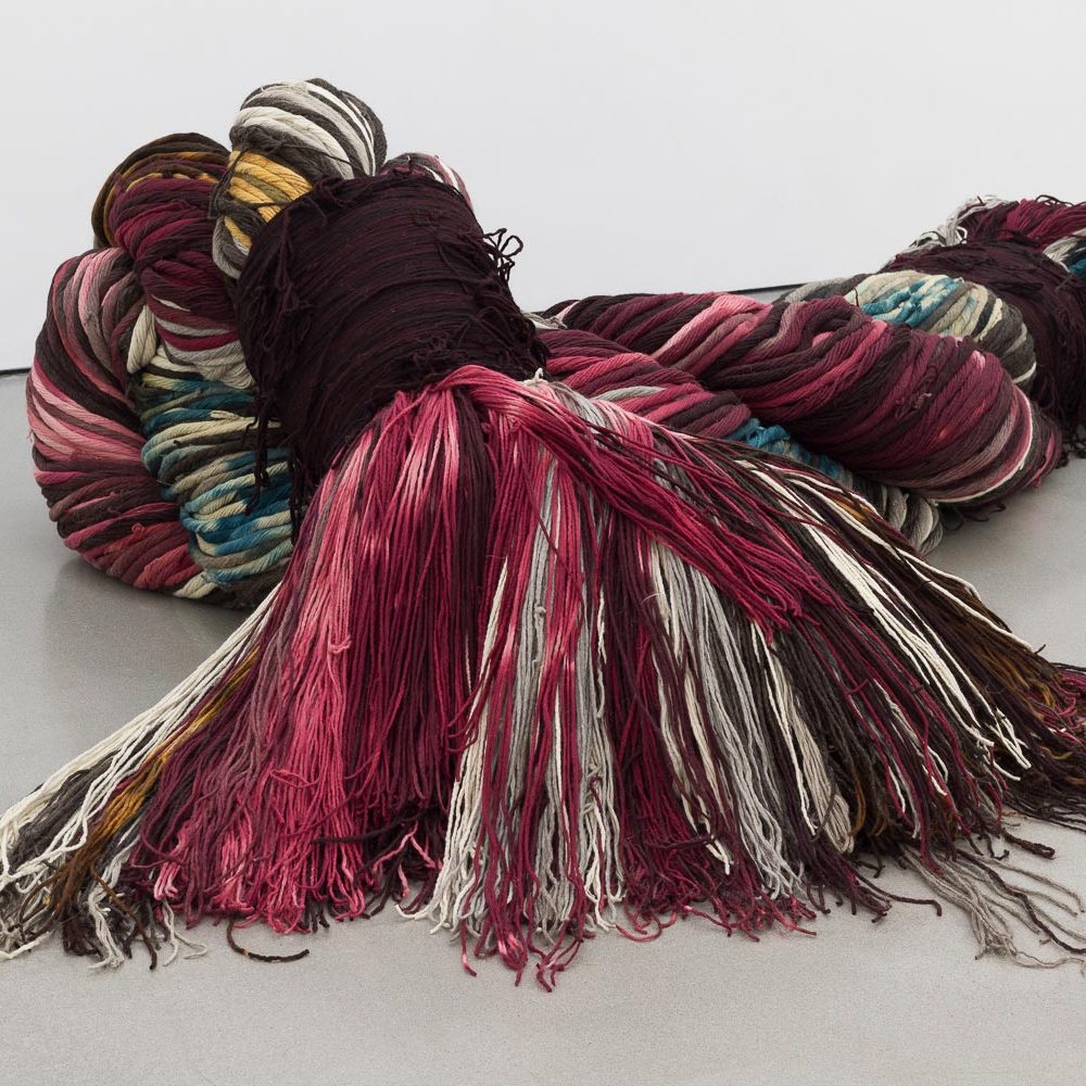 A large sculpture made up multiple strands of colourful material braided together to make a very thick rope.