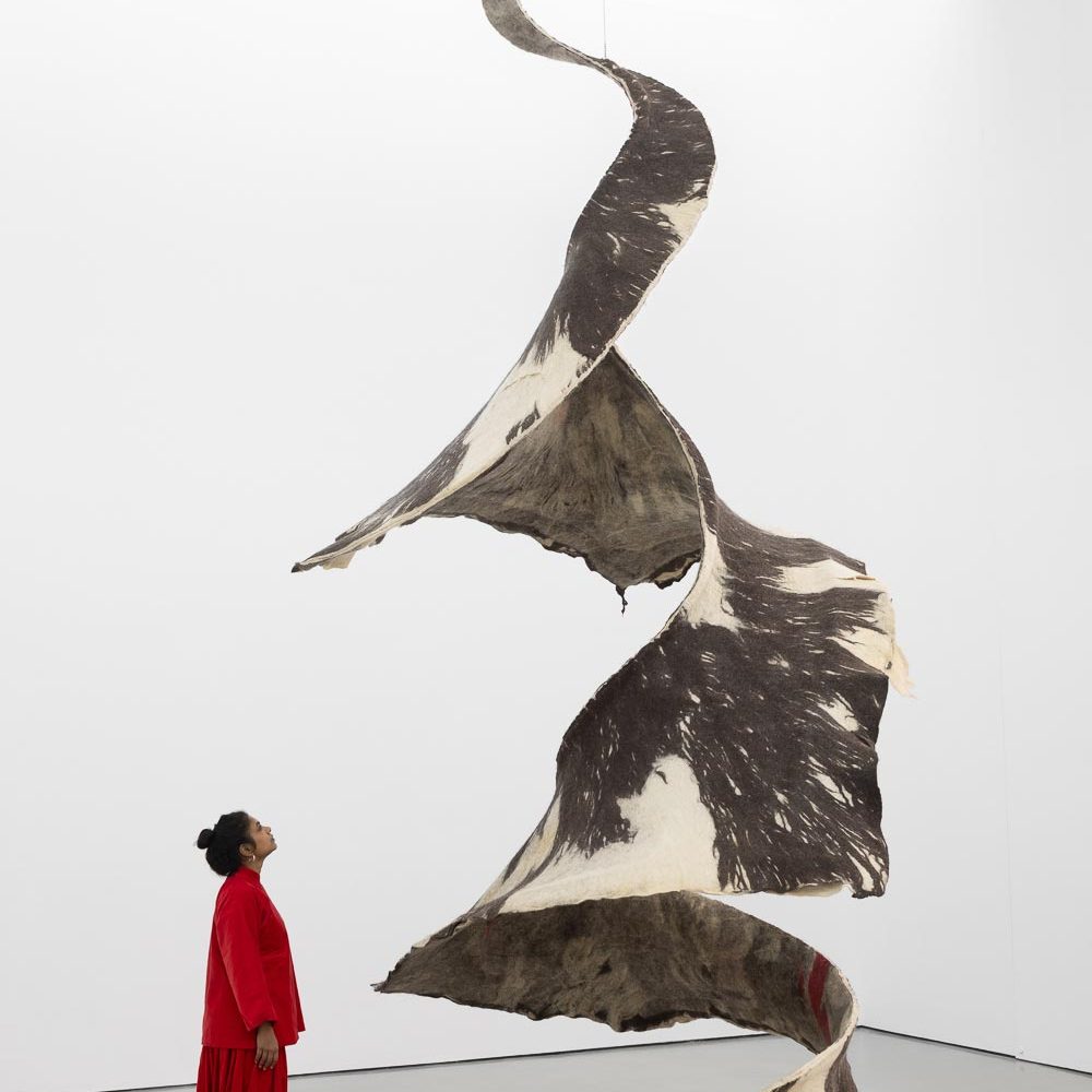 Artist Sagarika Sundaram standing next to her large fabric spiral-shaped sculpture 'Dancer'.