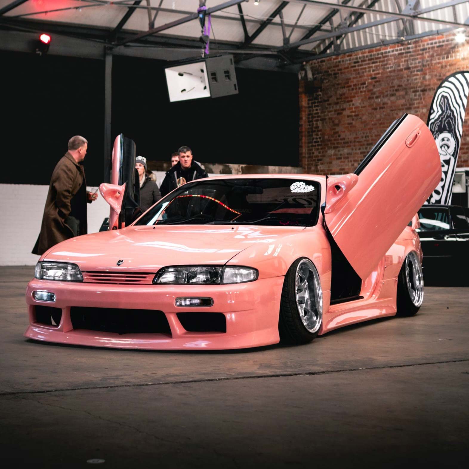 A powder-pink Nissan Silvia, with 'butterfly' doors open.