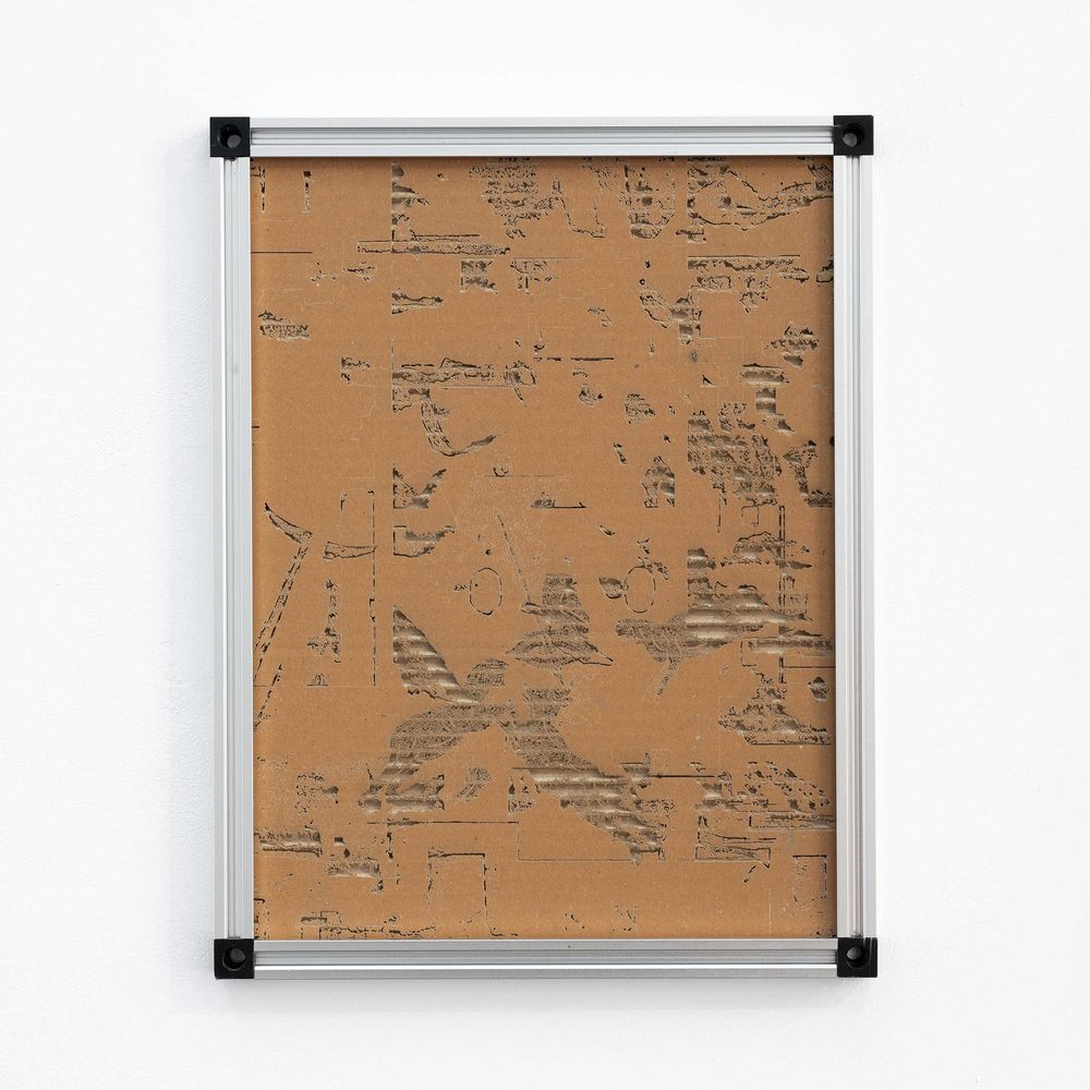 A metal-framed piece of cardboard. The top surface has been laser-engraved away with images of 'digital noise' to reveal the corrugation underneath.