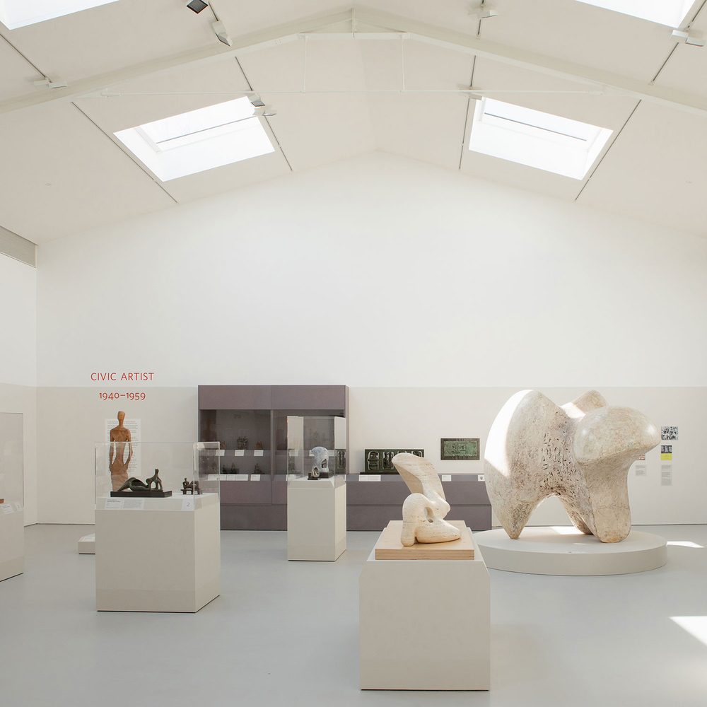 A large, airy gallery space showing many sculptures on plinths and in display cases.