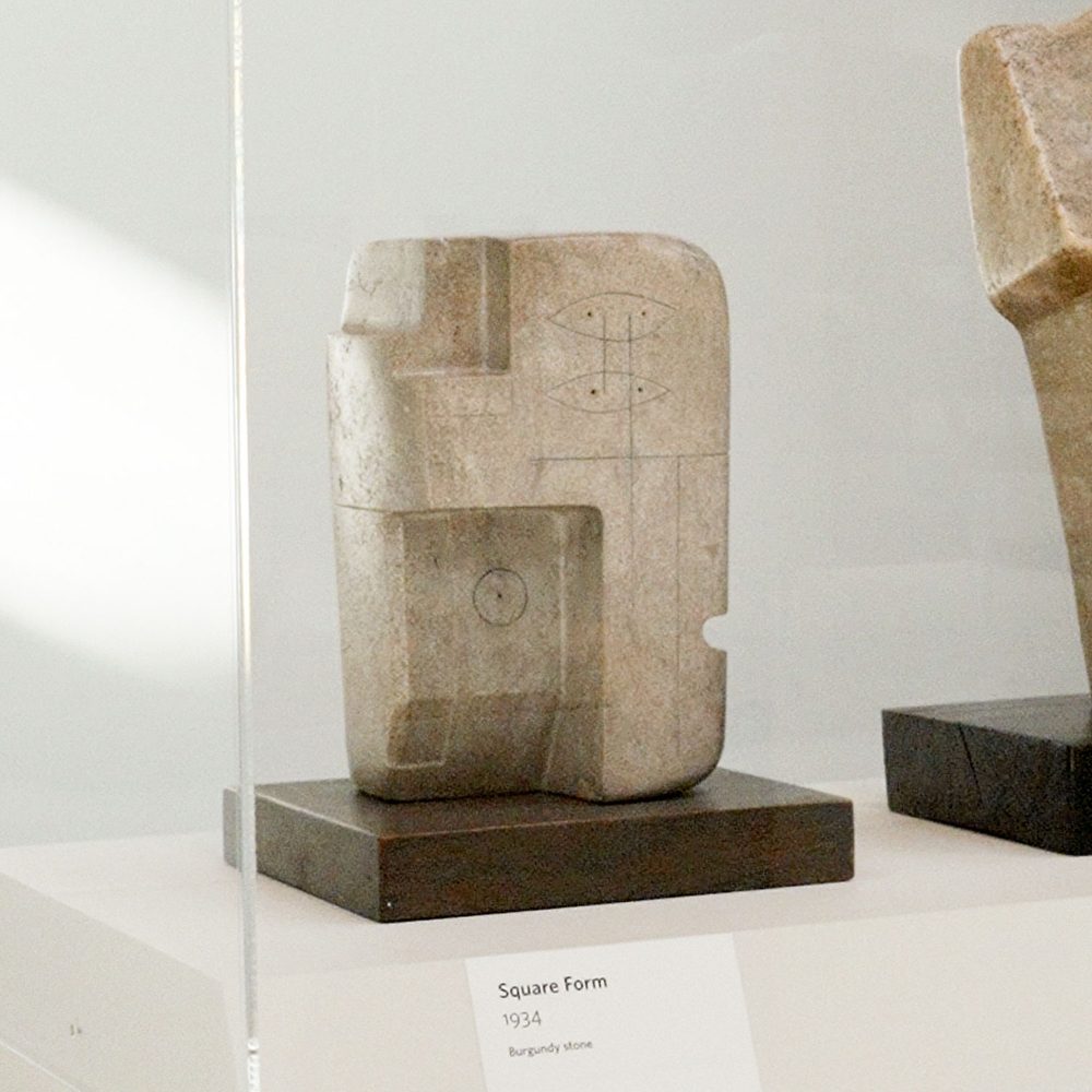 A solid block of roughly square stone with sections cut away. Lines drawn on the stone make it appear like a very abstracted human head.