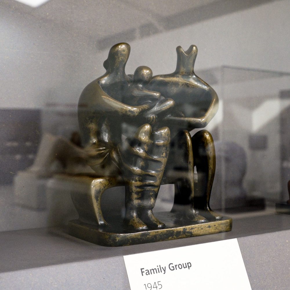 A small bronze sculpture of a seated woman and man, with a child held between them.