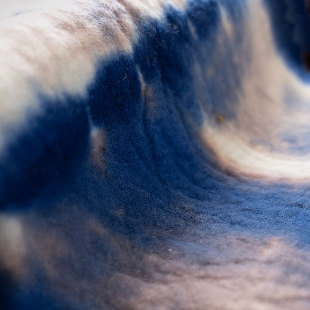 A piece of felt dyed blue and white, folded in a way that makes it look like a wave crashing.